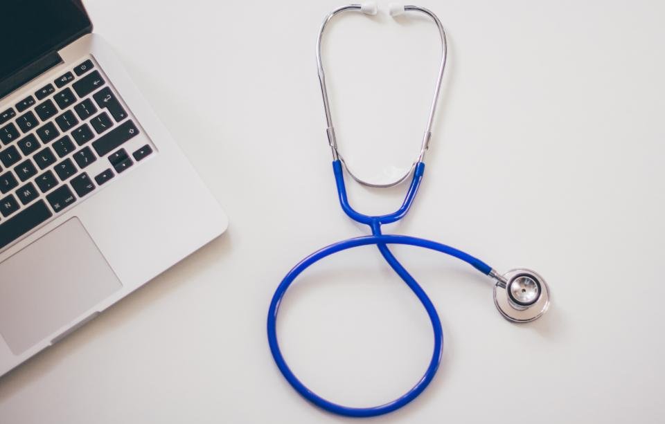 A stethoscope beside a laptop on a white desk