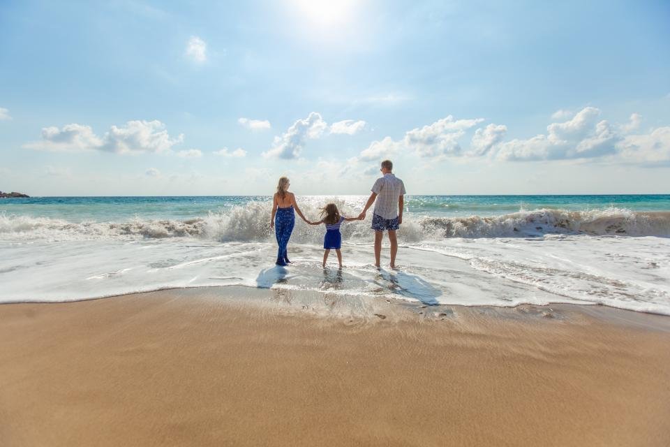 A family holding hands as they walk into the surf at the beach
