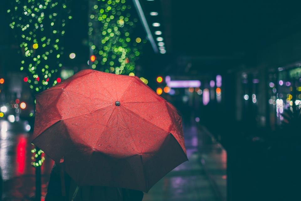 A person under a red umbrella on a rainy city street