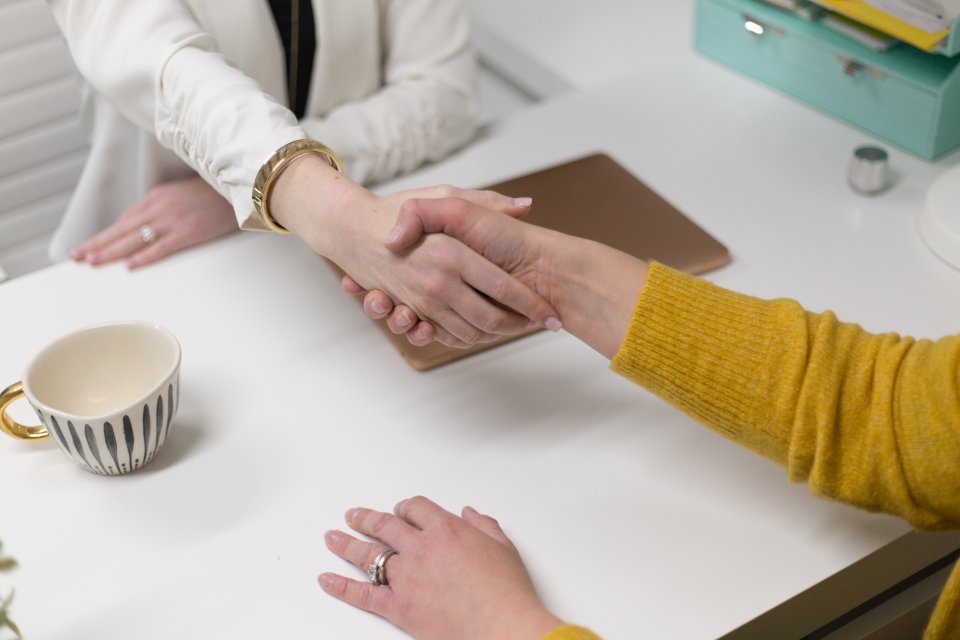 Two people shaking hands across a desk
