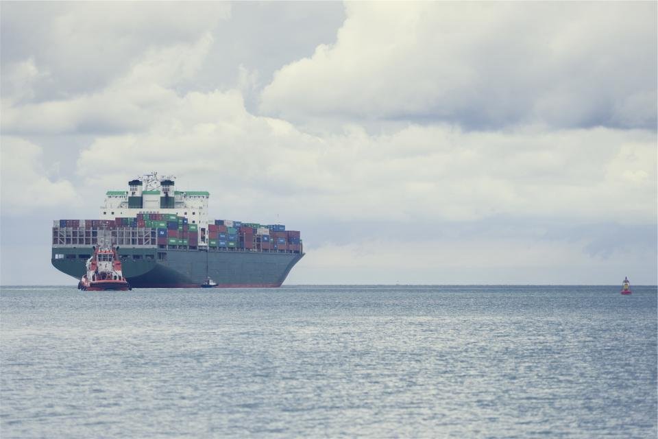 A container ship at sea with a tugboat alongside